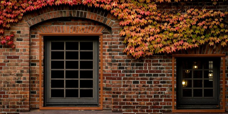 Brick home exterior with autumn leaves representing fall home maintenance in San Antonio