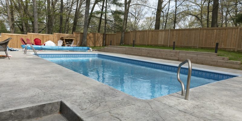 Rectangular backyard pool with surrounding deck suited to a San Antonio pool deck remodel